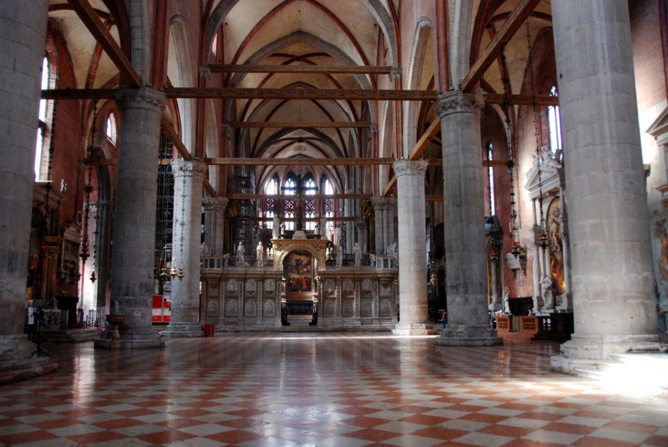 View of the nave of Santa Maria Gloriosa dei Frari, looking through the gate of the Schola Cantorum toward Titian's sumptuous Assumption of the Virgin over the high altar. Note that no tiles in the floor have been left missing for the sake of historical meaning.
[Image source]